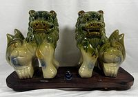 Front view of ceramic Shisa Foo Dog pair on wooden platform showing overall condition and glaze