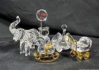 Five Swarovski crystal animal miniature figurines displayed against black backdrop with clear and gold accents visible.
