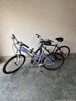 Two mountain bikes placed side by side on a garage floor: the blue Trek 800 Sport and black Schwinn Aluminum Comp.