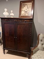 Front view of large antique wooden armoire with two large doors and four smaller drawers on top.