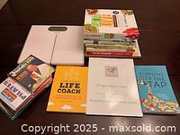 Image showing stack of seven books including cookbooks, life coaching, Pilates, and motivational books, next to the white digital bathroom scale.