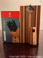Photo of boxed 7-piece J.A. Henckels Fine Edge Pro knife set and the striped hardwood cutting board with removable feet and wine bottle holder in front