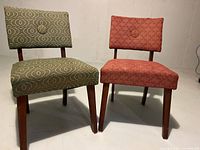 Front view of two mid century low chairs, one green and one red, positioned side by side.