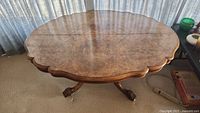 Full view of the antique round parlour table showing scalloped edges and central pedestal base with three legs.