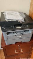 Front view of Brother multifunction printer with instruction manual placed on top