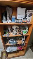 Overview photo of all items on shelf showing vacuum cleaner, lantern box, batteries, and iron.