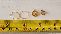 Overview of all three items: two hoop earrings and two pendants with measuring tape showing sizes.
