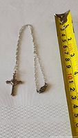 Full view of the sterling silver cross pendant necklace laid out showing chain length against a measuring tape for scale.