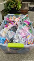 Plastic bin filled with many vintage McDonald's toys in original sealed bags, colorful, various characters and vehicles visible.