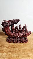 Front side view of cinnabar-colored resin statue showing the Boat of Life with eight human figures and detailed tree