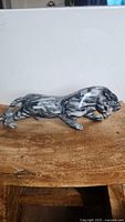 Side view of polished gray striped marble big cat statue on a wooden surface