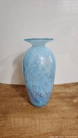 Front view of blue art glass vase showing flared rim, swirled blue and white marbled pattern.