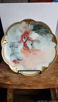 Front view of the signed vintage AKD hand-painted plate from France showing the hand-painted berry and leaf design with gold trim and scalloped edge.