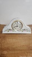 Front view of vintage Aynsley porcelain Napoleon mantel clock with floral Wild Tudor pattern and gold-gilded clock face