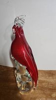 Left side view of the red Murano glass parrot figurine showing clear glass crest and base.