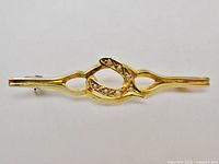 Top view of gold bar brooch with central horseshoe/wishbone motif and seed pearls