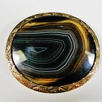 Top-down view showing oval banded agate with concentric stripes and engraved gold bezel