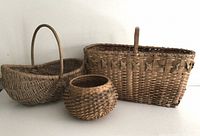 Three handwoven baskets of varying sizes showing front angle view, all natural fiber with rustic appearance