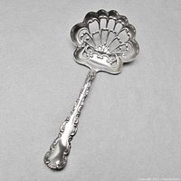 Top down view showing the pierced scalloped bowl and detailed Louis XV style handle of the sterling silver bonbon spoon.