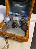 Velvet jewelry box open showing pendant and three pairs of coin-based jewelry pieces