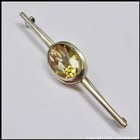 Close-up side angle showing the faceted oval citrine set in minimalist solid 835 silver bar brooch with a slender silver band.