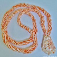 Full necklace laid out flat showing six-strand twisted coral bead rope and floral pendant