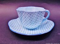 Front angled view of Shelley dainty cup and saucer showing blue star and polka dot pattern on pastel blue background with scalloped rims and blue trim edges.