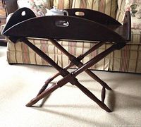 Side view of the butler's table showing the X-shaped mahogany legs and tray with carved handles.