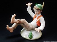 Front angle showing the boy with raised hands and legs, looking at the green frog on the base.