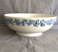 Side profile of the Wedgwood jasperware bowl showing cream body with detailed blue grapevine decoration around the sides.