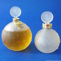 Both vintage frosted glass perfume bottles side by side on a blue background showing 'W' stoppers and star embossing.