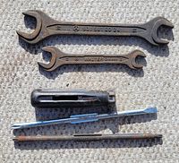 Photo showing six tools including two open-end wrenches with Mercedes-Benz and Walter branding, black plastic handle screwdriver, and several metal bits/tools with rust and wear.