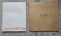Two Corvette brochures side by side; white cover with red lettering and beige leather-textured cover with emblem.