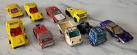 Front-view close-up of the lot showing 10 vintage toy cars arranged in two rows on a white surface.
