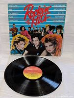 Photo of the vinyl LP record with cover upright showing front artwork and vinyl disc removed and laid flat, showing label and vinyl surface condition.