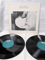 Photo of the double vinyl LP records with blue-green labels laid out with the album cover behind them.