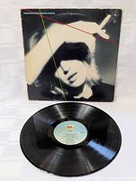 Full photo of the black vinyl LP with blue label, laid flat with the album cover behind it, showing good groove condition and no obvious major scratches.