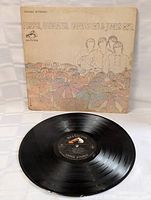 Vintage LP album cover titled 'Pisces Aquarius Capricorn & Jones Ltd.' by The Monkees with visible illustrated design showing band members and umbrella motifs. Vinyl record with RCA Victor label placed in front of cover.