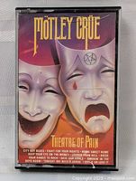Front cover of the cassette tape showing the theatrical mask artwork and song list.