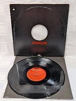 Vinyl record partially out of black Polydor sleeve showing wear and logos.
