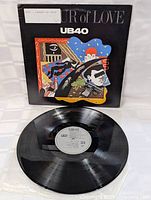 Vinyl record shown outside cover with label visible indicating UB40 and 33 RPM speed.