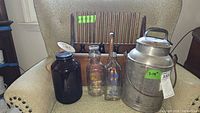 Full view of wooden cranberry scoop, metal milk jug, and vintage glass bottles on spool rack chair