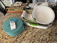 Full view of all items on countertop including teal Dansk covered stockpot, two white roasting pans stacked, and large white enamelware bowl