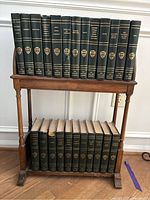 Two shelves filled with green hardcover Harvard Classics books with gold embossed titles and shield emblems on spines. Some books show spine damage and wear.