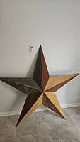 Large 3D metal and wood star wall decor hanging on wall, showing full front view with variegated metal and wood finishes and rivet detailing.