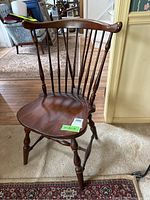 Front angled view showing curved top rail, spindle backrest, contoured seat, turned front legs, and stretcher.