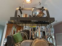 Metal ceiling mounted pot rack from a downward angle showing grid surface, metal hooks and two arching supports.