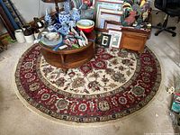 Round area rug under a wooden circular table with decorative items on top.