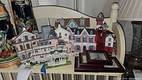 Photo of several colorful Cape May house replicas including a red lighthouse and a small shrine, all placed on a chair
