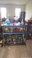 Full front view of the vintage bar serving cart with various glass and decorative items displayed, not included in sale.